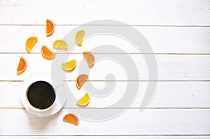 White cup of coffee and multi-colored fruit marmalade on a white wooden table