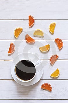 White cup of coffee and multi-colored fruit marmalade on a white wooden table