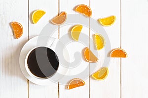 White cup of coffee and multi-colored fruit marmalade on a white wooden table