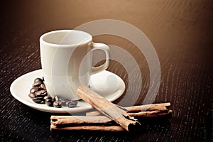 White cup with coffee near coffee beans over wood table