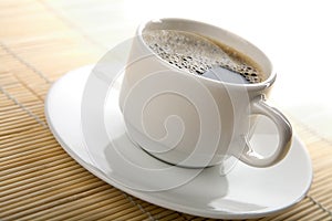 White cup of coffee over bamboo background