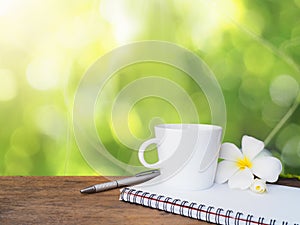 White cup of coffee, pen and notepad on wooden table