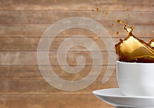 White cup with coffee splashing against blurry wood panel