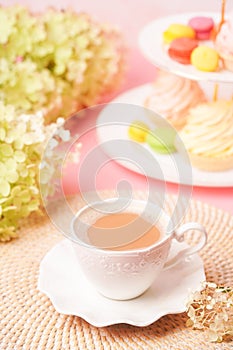 a white cup of coffee with sweets and a bouquet of flowers in soft, pastel colors.