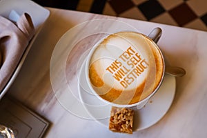 White cup of coffee with text on marble background. Table setting in the restaurant