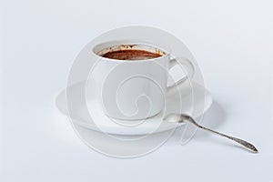 White cup with coffee on tha saucer, and metallic teaspoon isolated on white background