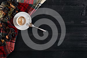 White cup of the coffee and vintage scarf on black wooden background