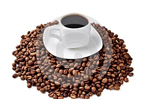 White cup of coffee on a white saucer stands on a hill of coffee beans on a white background  angle view from above