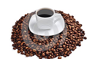 White cup of coffee on a white saucer stands on a hill of coffee beans on a white background  angle view from above