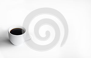 White cup of coffee on a white table with place for text. Top view