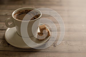 White Cup of coffee on wood natural background cane sugar pieces on plat