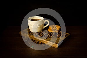 White cup of coffee on wooden tray with cookies and coffee beans photo