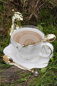 White cup with cold coffee drink on green grass outdoors