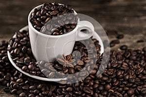White cup covered coffee beans with star anise