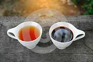 White cup of earl grey tea and coffee on wooden background