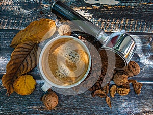 White cup of espresso on a wooden surface with yellow leaves.