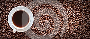 white cup filled with coffee on a background of coffee beans. long banner. view from above