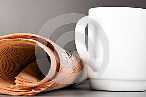 White cup and folded newspaper