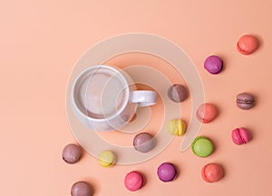 White Cup of fragrant cappuccino with macarons cakes on orange background