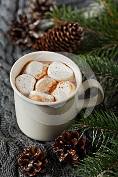 White cup of fresh hot cocoa or hot chocolate with marshmallows on grey knitted background