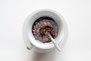 White cup full of coffee beans, on a white background