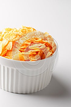 White cup with golden corn flakes isolated on white background. View from above. Delicious and healthy breakfast