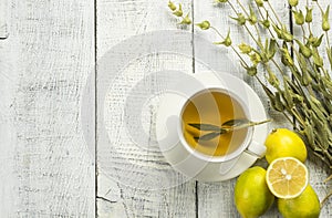 white cup of herbal sage tea with dried sage leaves and lemon on white wooden rustic background