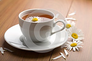 White cup of herbal tea and camomile flowers