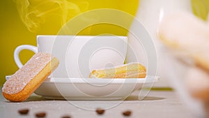 White cup of hot aromatic coffee, a jug of milk and savoiardi biscuits or ladyfingers cookies