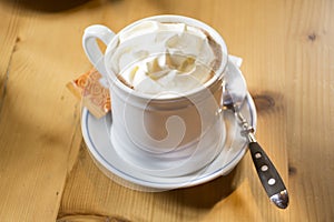 White cup with hot chocolate topping whipped cream serve with sugar bag