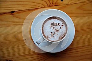 White cup of hot coffee latte on brown wooden table