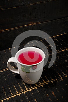 White cup of kissel or jelly berry drink on black wooden background. Vitamin hot beverage from avitaminosis