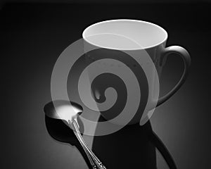 White cup with metal spoon on black background