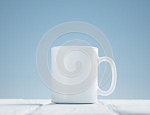 White cup mock-up inclined on wooden table photo