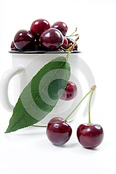 White cup with red sweet cherry isolated on a white background.