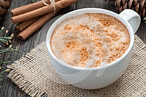 White cup of salep milky traditional hot drink of Turkey with cinnamon powder and sticks on rustic vintage wooden table photo