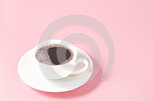 white cup with a saucer on a pink background/white cup of espresso with a foam on a pink background, selective focus and copy