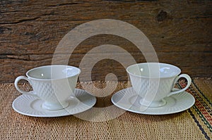 White cup and saucer set for hot coffee on papyrus mat