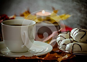 White cup and saucer with tea, coffee on table, maple leaves