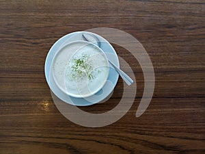 A white cup of soft drink is MATCHA Green tea late on wooden table