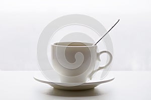 White cup with spoon and saucer on white background