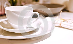 A white cup stands on two white saucers on a table