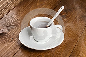 White cup of steamy coffee on wooden table