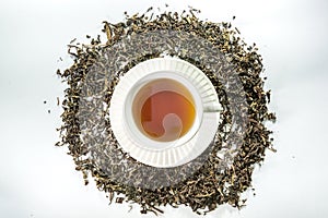 White cup of tea with dried tea leaf