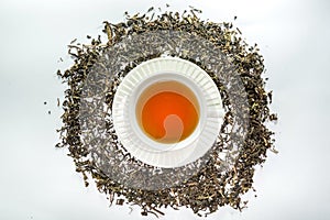 The White cup of tea with dried tea leaf