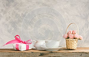 White cup with tea, gift box, basket with roses