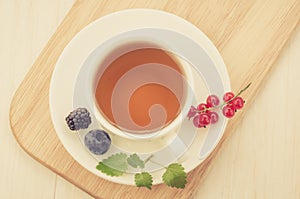 white cup tea with mint and berries in a saucer/white cup tea with mint and berries in a saucer on a wooden tray and a white