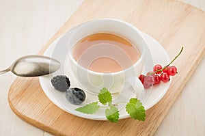 White cup tea with mint and berries in a saucer/white cup tea wi