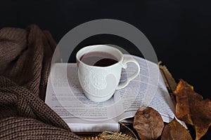 Cup of tea on book and autumn decorated black desk with copy space