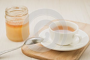 White cup of tea with an open jar of honey/white cup of tea with